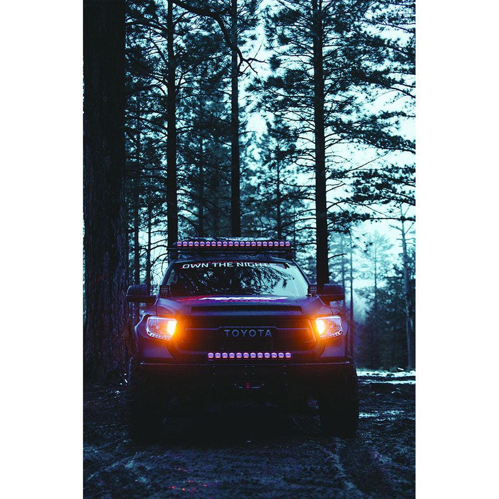 Toyota truck equipped with Rigid Industries 20-inch Adapt black LED light bars in a forest setting at dusk