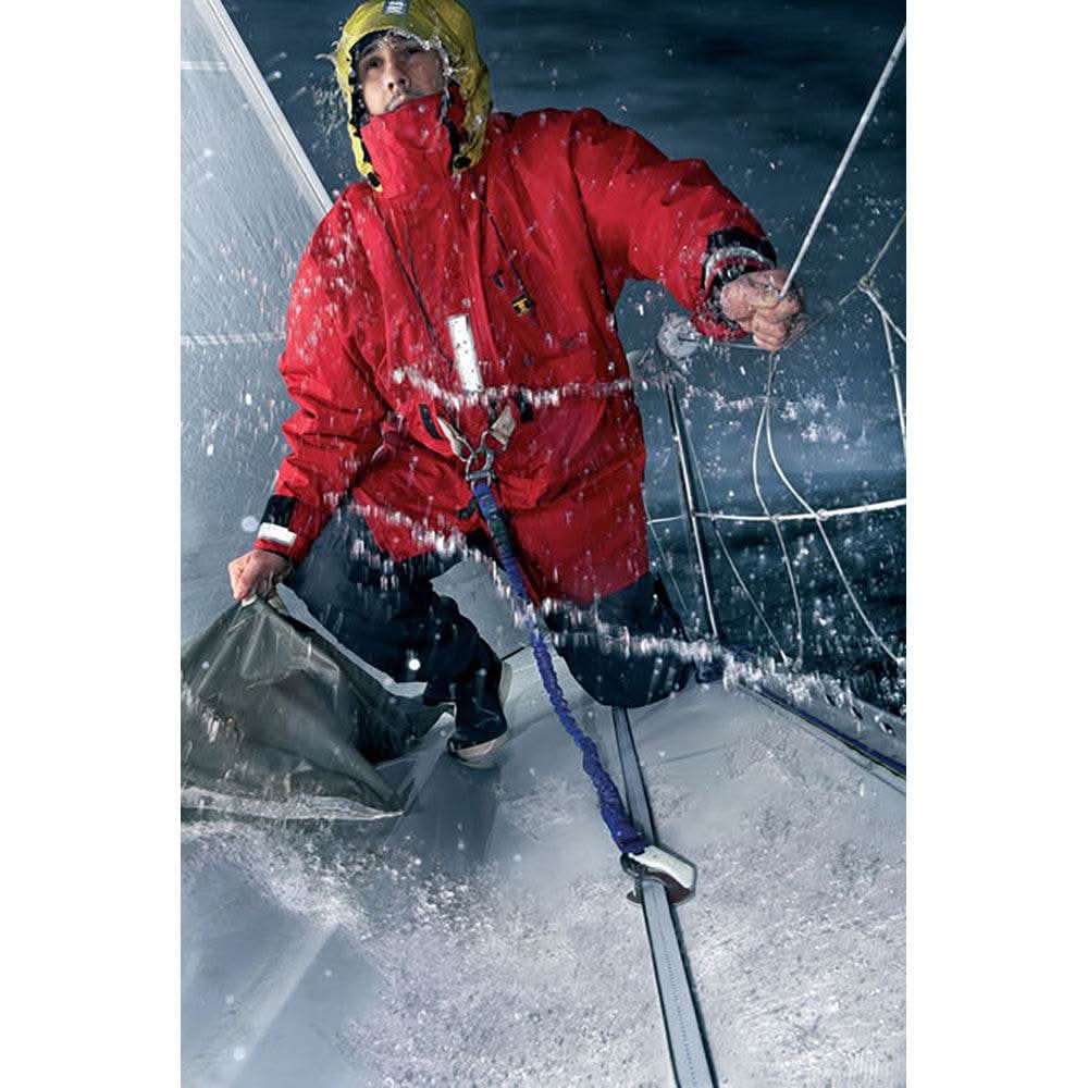 Sailor wearing red jacket secured with Lyf'Safe Jackline Kit on wet sailboat deck at night